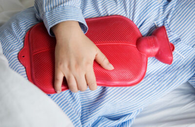 A woman in pain holding a hot water bottle