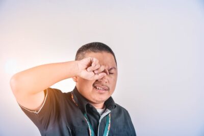 a man is rubbing his eyes because of itching and irritation