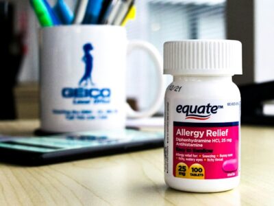 A bottle of equate brand allergy medicine on an office desk in daylight