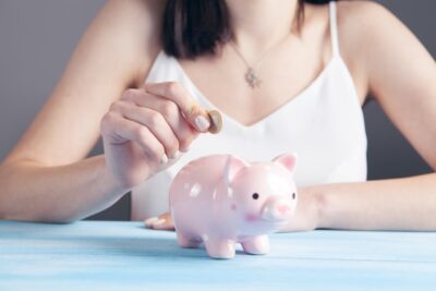 Woman putting coin in piggy bank